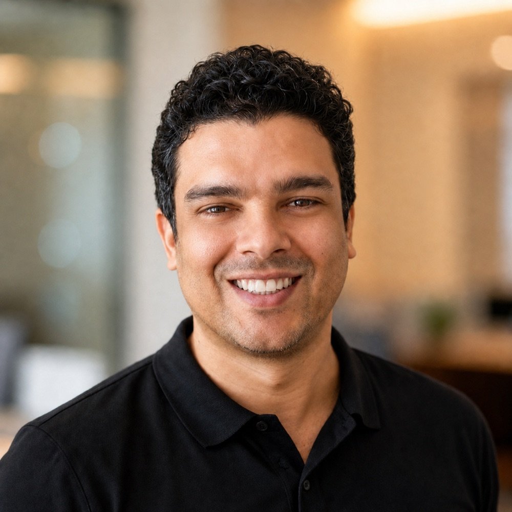 Daniel Bezerra sorrindo, vestindo camisa polo preta